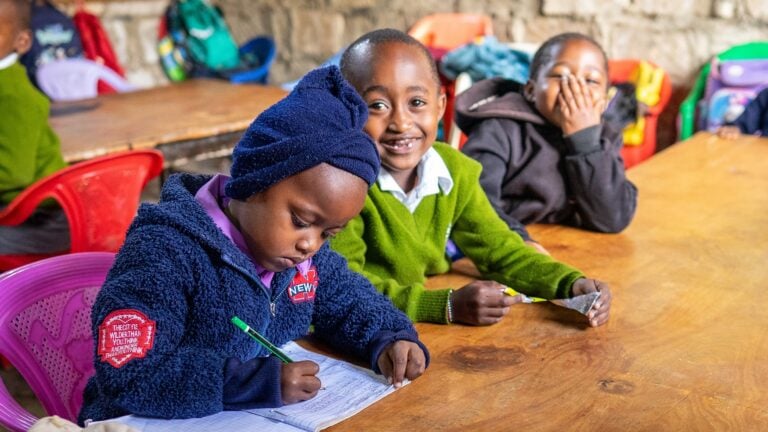 students in Kenya smiling at desks