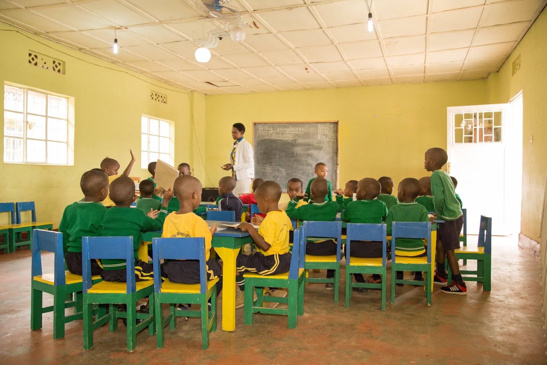 students in Rwandan classroom raising hands